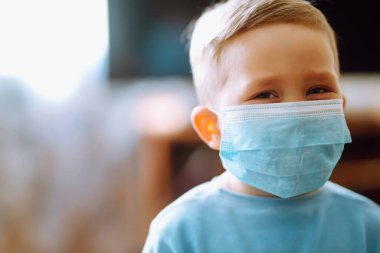Koruyucu steril tıbbi maske takan küçük bir çocuk. Çocuk, yüz maskesi takıyor, karantina şehrinde virüs, salgın ve salgın hastalıklardan korunuyor. Covid 2019.