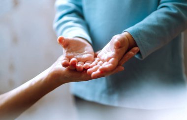 Annem ellerini yıkamasına yardım ediyor. Ellerini birbirine sürterek sabunla köpük oluşturuyorlar. Hijyen konsepti. Mikropların ve bakterilerin yayılmasını önle ve koronavirüsün bulaşmasını önle.