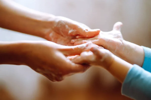 Annem ellerini yıkamasına yardım ediyor. Ellerini birbirine sürterek sabunla köpük oluşturuyorlar. Hijyen konsepti. Mikropların ve bakterilerin yayılmasını önle ve koronavirüsün bulaşmasını önle.