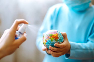 Gezegen sterilizasyonu. Dünya küresi tutan steril tıbbi maskeli bir çocuk. Gezegeni kurtar. Salgın koronavirüsün yayılmasını önleme konsepti.