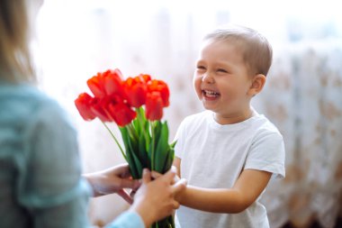 Küçük oğlu annesini tebrik ediyor ve bir buket çiçek lalesi veriyor. Anneler Günün kutlu olsun. Aile tatili ve birliktelik.