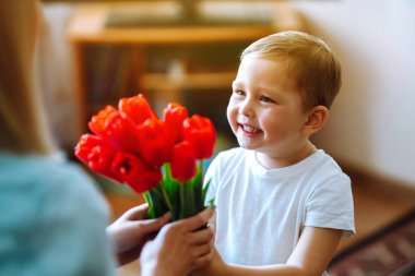 Küçük oğlu annesini tebrik ediyor ve bir buket çiçek lalesi veriyor. Anneler Günün kutlu olsun. Aile tatili ve birliktelik.