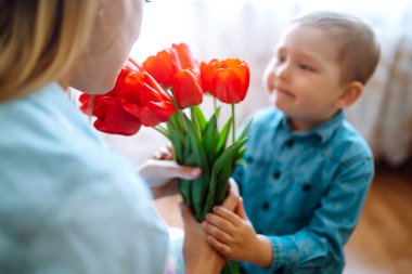Annem için bir buket lale. Küçük oğlu annesini tebrik ediyor ve bir buket çiçek lalesi veriyor. Anneler Günün kutlu olsun. Aile tatili ve birliktelik.