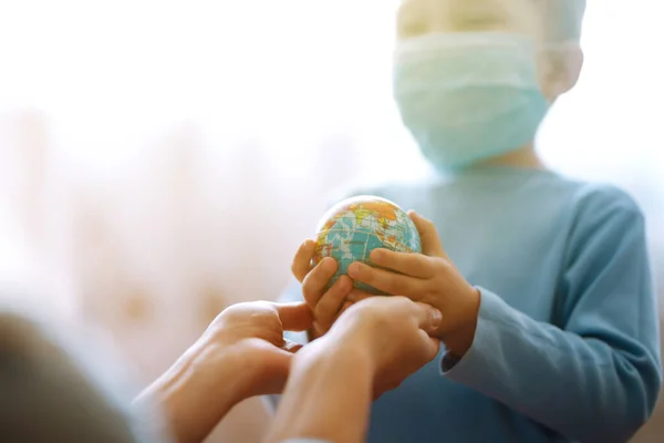 世界を保持する母親と保護滅菌医療マスクの子供 地球を救え 流行性コロナウイルスの拡散を防止する概念 — ストック写真