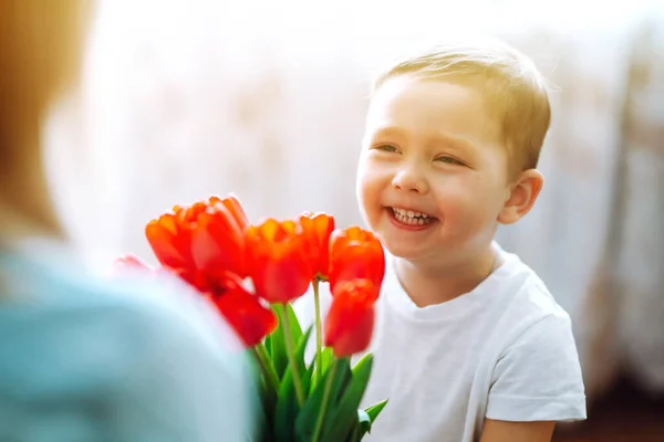 Little son congratulates mother and gives a bouquet of flowers tulips. Happy mother's day. Family holiday and togetherness.