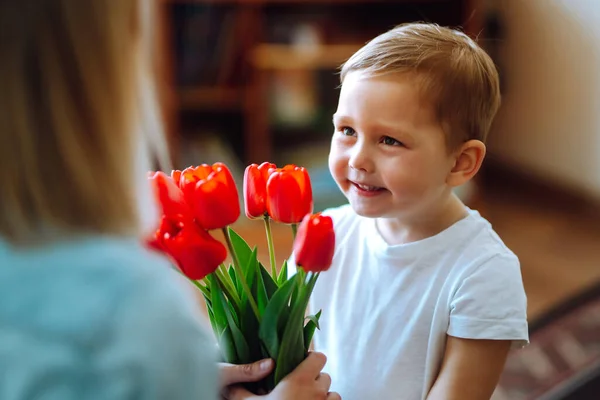Little son congratulates mother and gives a bouquet of flowers tulips. Happy mother\'s day. Family holiday and togetherness.
