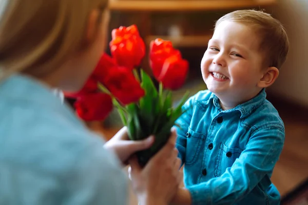 Little son congratulates mother and gives a bouquet of flowers tulips. Happy mother's day. Family holiday and togetherness.