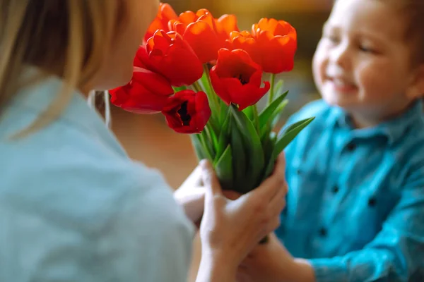 Bouquet of tulips for mom. Little son congratulates mother and gives a bouquet of flowers tulips. Happy mother\'s day. Family holiday and togetherness.