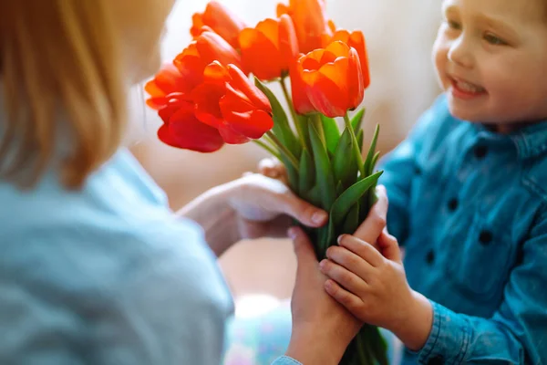 Bouquet of tulips for mom. Little son congratulates mother and gives a bouquet of flowers tulips. Happy mother\'s day. Family holiday and togetherness.