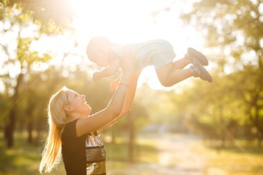 Mutlu anne bebeği kusar, güler ve doğada oynar. Anneler Günün kutlu olsun. Aile tatili ve birliktelik.