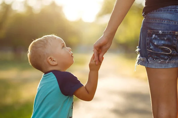 Close up of mother and a child hands at the sunset. Mom and son walk in the park. Family holiday and togetherness. Summer concept.