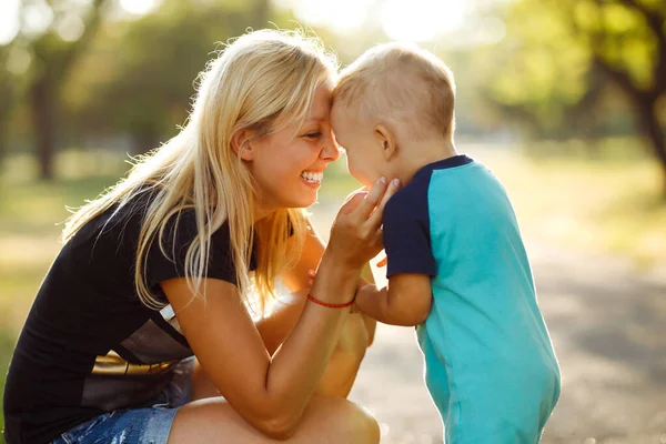 Kiss and hugs of mom and son. Mom and son walk in the summer park. Family holiday and togetherness. Happy mother\'s day.