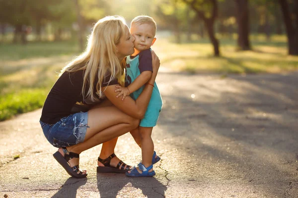 Kiss and hugs of mom and son. Mom and son walk in the summer park. Family holiday and togetherness. Happy mother\'s day.