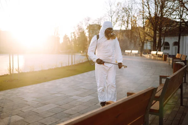 身穿防护服的男子在公共场所用喷雾化学品消毒 以防止这种流行病在检疫城市的蔓延 Covid 清洗概念 — 图库照片
