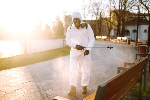 身穿防护服的男子在公共场所用喷雾化学品消毒 以防止这种流行病在检疫城市的蔓延 Covid 清洗概念 — 图库照片