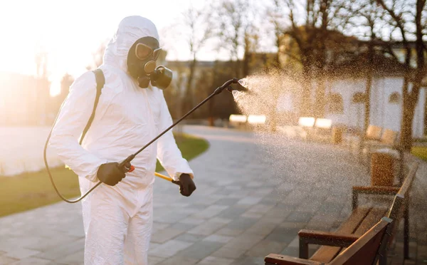 Man wearing protective suit disinfecting public places in the sun with spray chemicals to preventing the spread of coronavirus, pandemic in quarantine city. Covid -19. Cleaning concept.