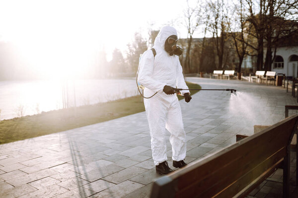 Человек в защитном костюме и маске вируса дезинфицирует общественные места с помощью спрея химических веществ, чтобы предотвратить распространение коронавируса. Превентивная инфекция и контроль над ней. Ковид-19
.