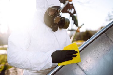 Koruyucu kıyafet giyen adam karantina şehrinde salgın olan koronavirüsün yayılmasını önlemek için oyun alanını temizliyor ve dezenfekte ediyor. Covid -19. Temizlik ve Dezenfeksiyon.