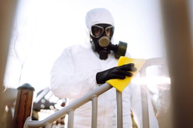 Korunaklı kıyafetli bir adamın eli, karantina şehrindeki koronavirüs salgınının yayılmasını önlemek için oyun alanını yıkıyor ve dezenfekte ediyor. Covid 19.