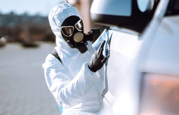 Hand of Man in protective suit washing and disinfection handles of a car, to preventing the spread of the epidemic of coronavirus, pandemic in quarantine city.