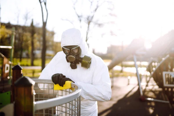 Hand of Man in protective suit washing and disinfection the playground, to preventing the spread of the epidemic of coronavirus, pandemic in quarantine city. Covid-19.