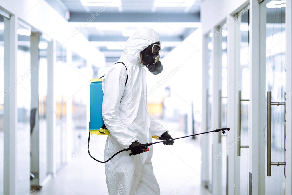 Disinfecting of office to prevent COVID-19, Man in protective hazmat suit with  with spray chemicals to preventing the spread of coronavirus, pandemic in quarantine city. Cleaning concept.