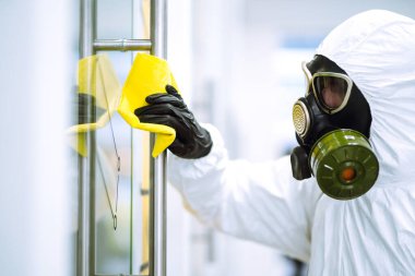 COVID-19 'u önlemek için ofisin temizlenmesi ve dezenfekte edilmesi koruyucu koruyucu koruyucu koruyucu koruyucu giysili adam Coronavirus' un yayılmasını önlemek için ofis mobilyalarını yıkıyor..