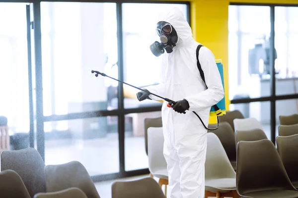 Hombre Con Traje Protector Desinfectando Salón Reunión Con Productos Químicos — Foto de Stock