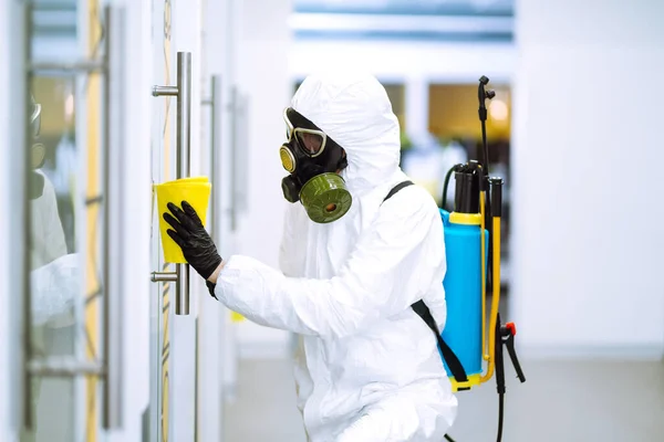 防護服を着た男は 隔離された都市でのパンデミックであるコロナウイルスの拡散を防ぐために 事務所でドアハンドルを洗う オフィスの清掃と消毒 Covid — ストック写真