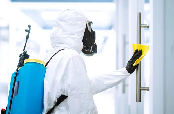 防護服を着た男は 隔離された都市でのパンデミックであるコロナウイルスの拡散を防ぐために 事務所でドアハンドルを洗う オフィスの清掃と消毒 Covid — ストック写真