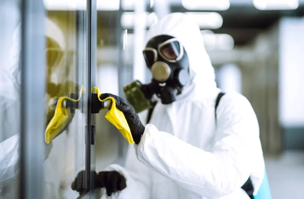 Cleaning and disinfection of office to prevent COVID-19, Man in protective hazmat suit washes office furniture to preventing the spread of coronavirus, pandemic in quarantine city.