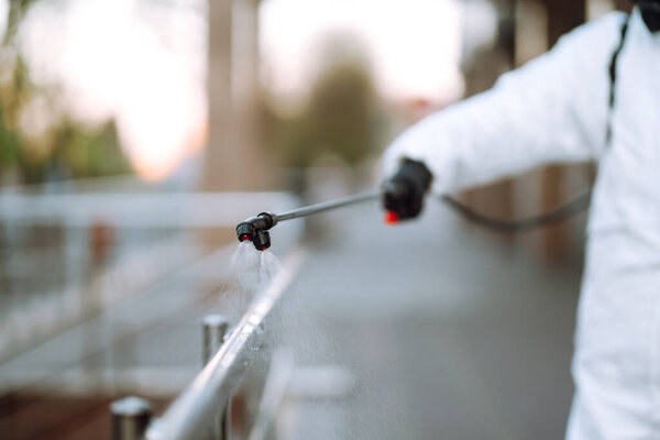 Disinfectant sprayers with spray chemicals onto the railing in the empty public place at dawn in the city of quarantine. Covid -19. Cleaning concept.
