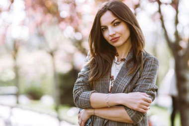 Çiçek açan bahar ağacının yanında güzel genç bir kadın. Parkta eğlenen çekici bir kız. Bahar geldi..