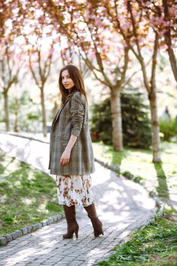 Çiçek açan bahar ağacının yanında güzel genç bir kadın. Parkta eğlenen çekici bir kız. Bahar geldi..