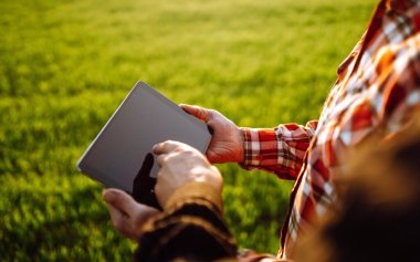 Tarlada tabletli çiftçiler. Tarladaki buğday kalitesini kontrol etmek için dokunmatik ped kullanan çiftçiler. Tarım sektörü kavramı.
