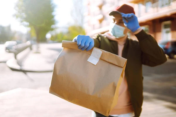 保護マスクと医療用手袋の宅配便は 食品と紙パケットを保持しています 隔離された街のスクーターで配達サービス Covid — ストック写真
