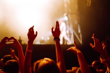 Müzik festivalinde el kaldıran kalabalık. Taraftarlar ışık gösterisi ve alkışlarla rock konserinin keyfini çıkarıyorlar.