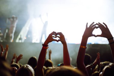 Kalp şeklinde eller konserde, sanatçıya ve festivale bayılıyor. Konserden keyif alan insanların ışık ve siluetiyle müzik konseri.
