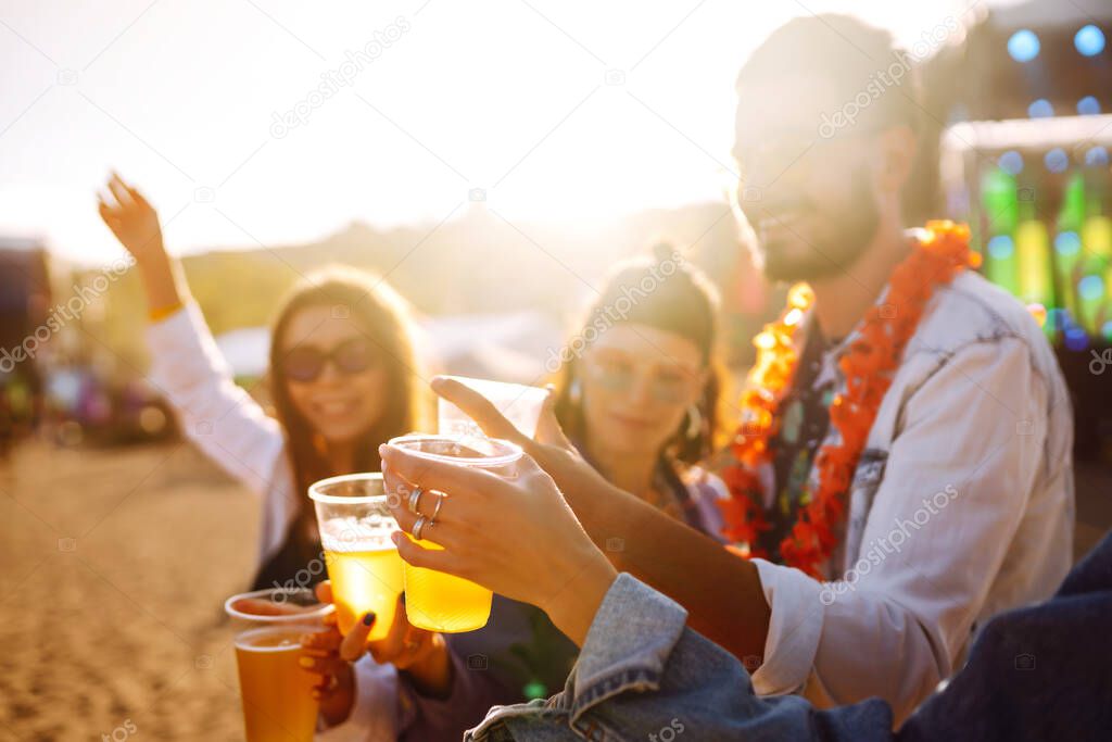 Young happy friends drinking beer and having fun at music festival together. Beach party, summer holiday, vacation concept. Friendship and celebration concept.