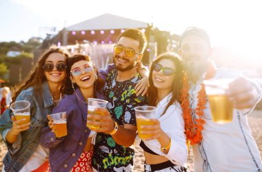 Genç mutlu arkadaşlar bira içiyor ve müzik festivalinde birlikte eğleniyorlar. Plaj partisi, yaz tatili, tatil konsepti. Arkadaşlık ve kutlama konsepti.