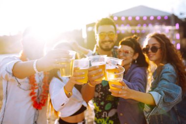 Genç mutlu arkadaşlar bira içiyor ve müzik festivalinde birlikte eğleniyorlar. Plaj partisi, yaz tatili, tatil konsepti. Arkadaşlık ve kutlama konsepti.