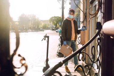 Karantina şehrinde kurye bir torba yiyecek getiriyor. Teslimat hizmeti konsepti. Covid 2019.