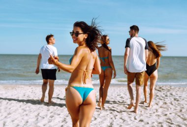 Bir grup arkadaş sahilde koşup eğleniyorlar. Genç arkadaşlar plaj tatilinin tadını çıkarıyorlar. Yaz, rahatla ve yaşam tarzı kavramı.