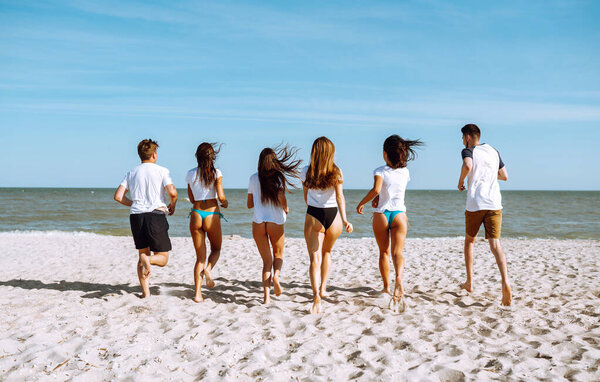 Group of friends run to swim in the sea. Summer holidays, vacation, relax and lifestyle concept.