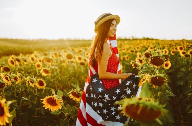 4 Temmuz. Ayçiçeği tarlasında Amerikan bayrağıyla şapkalı harika bir kız. Özgürlük günü. Gün batımı ışığı. Bağımsızlık Günü. Vatansever kavram