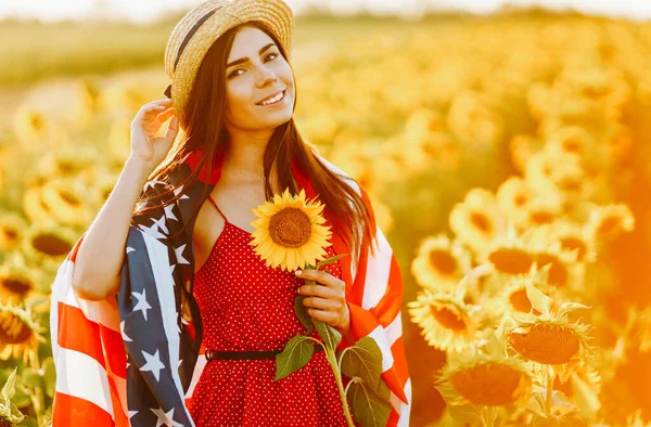 4 Temmuz. Ayçiçeği tarlasında Amerikan bayrağıyla şapkalı harika bir kız. Özgürlük günü. Gün batımı ışığı. Bağımsızlık Günü. Vatansever kavram