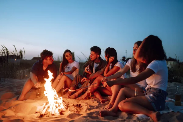 Gruppo Giovani Amici Seduti Sulla Spiaggia Friggere Salsicce Uomo Sta — Foto Stock