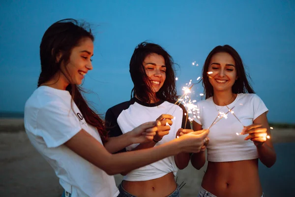 Trzy Piękne Dziewczyny Świętują Trzymając Ognie Plaży Nocy Młodzi Nastolatkowie — Zdjęcie stockowe