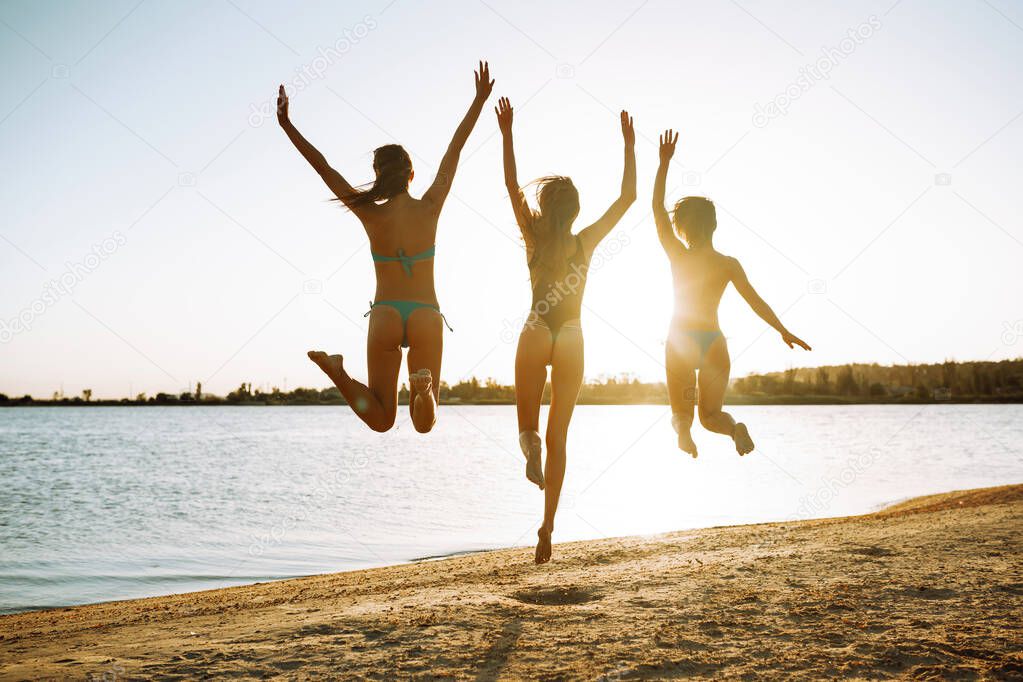 Happy girls jumping on the beach. Summer holidays, vacation, relax and lifestyle concept.