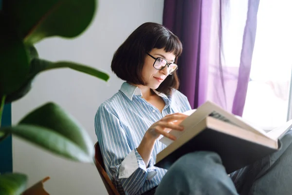 Seorang Wanita Muda Membaca Buku Rumah Duduk Kursi Modern Santai — Stok Foto